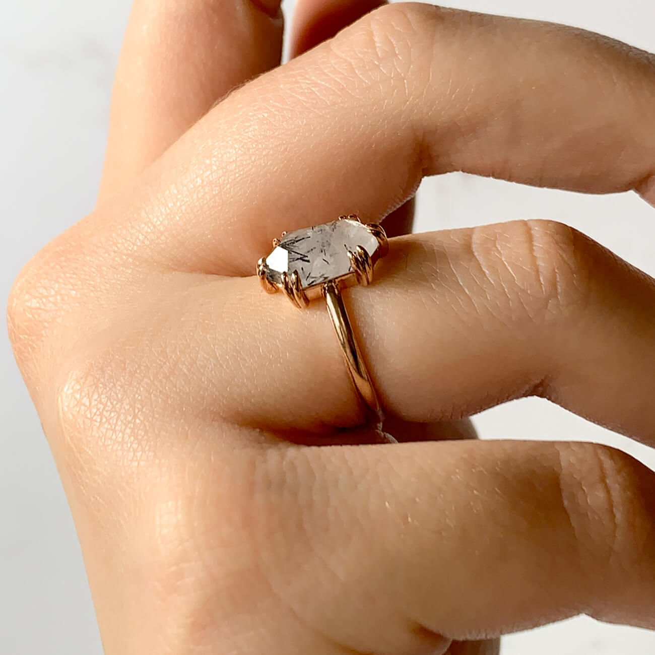 Hexagon cut tourmalated quartz ring on a hand