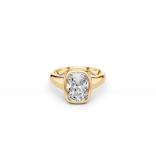 Bezel set elongated cushion-cut ring with puffy gold silhouette in yellow gold