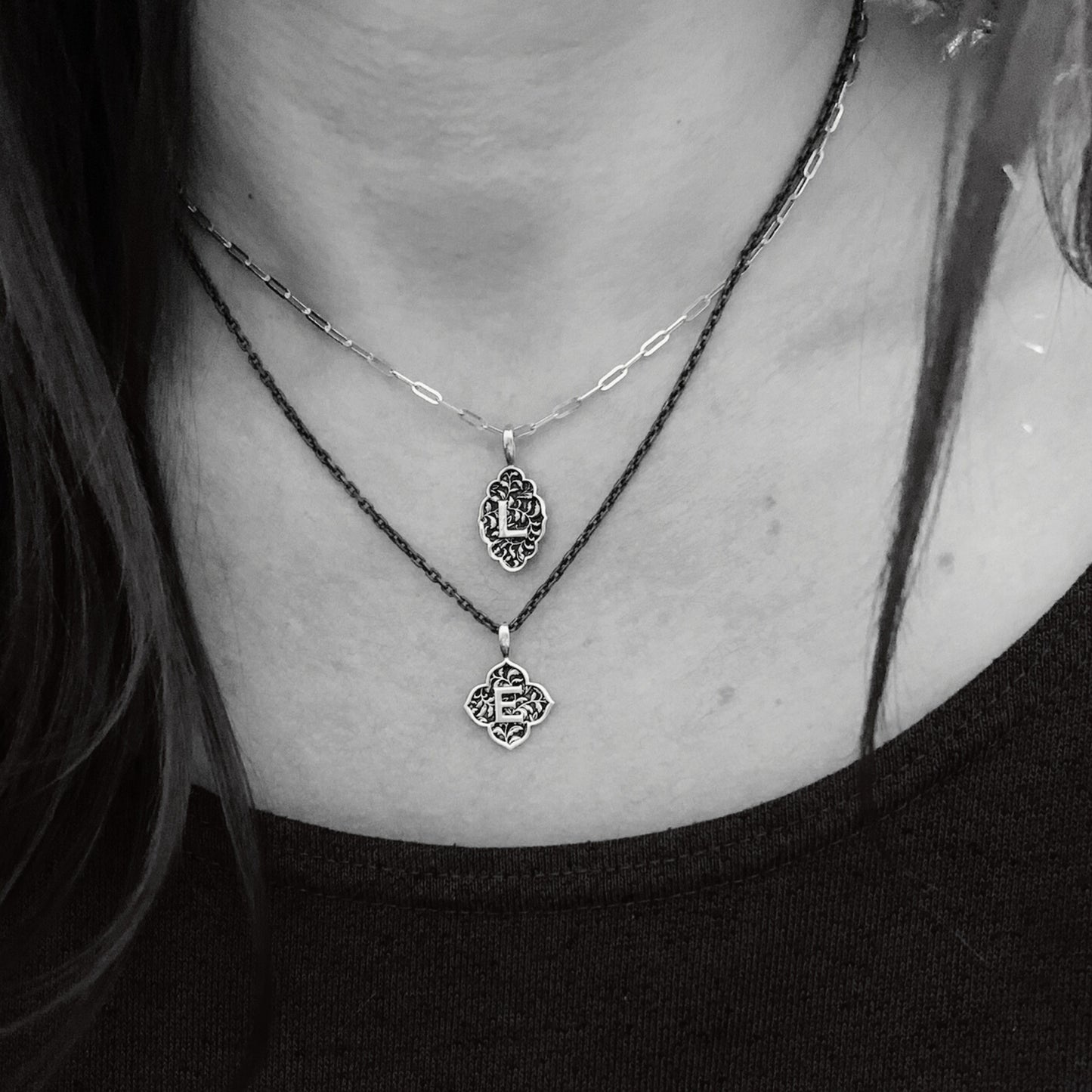 Model wearing silver clover love letter initial pendant on blackened silver chain